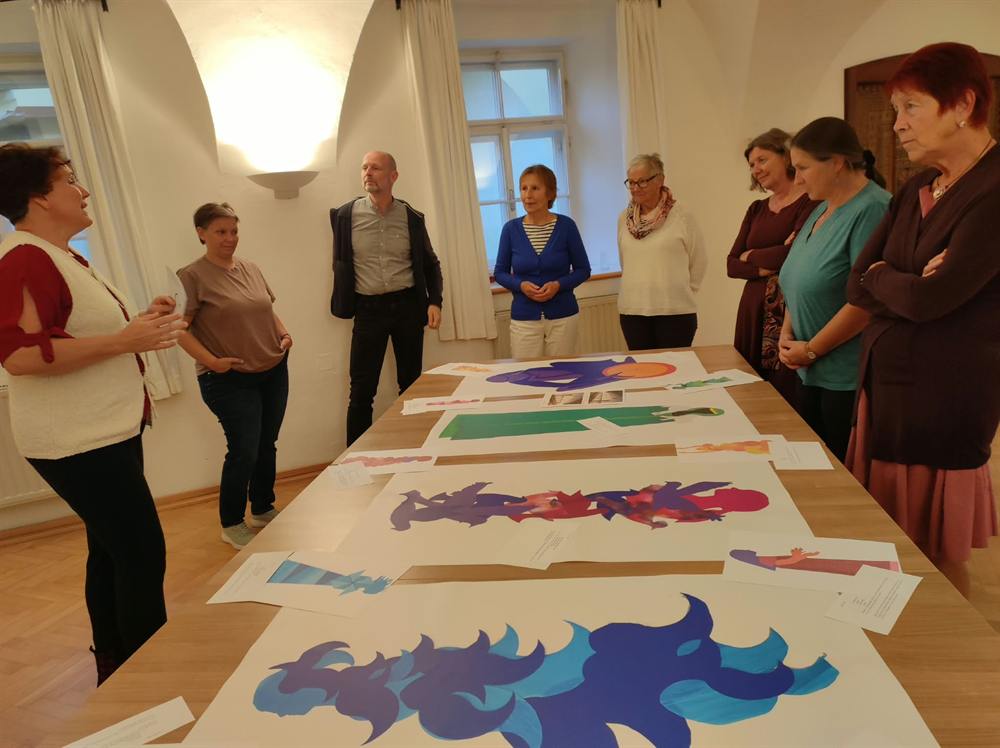 Gruppe gestaltet bunte Bilder auf einem langen Tisch