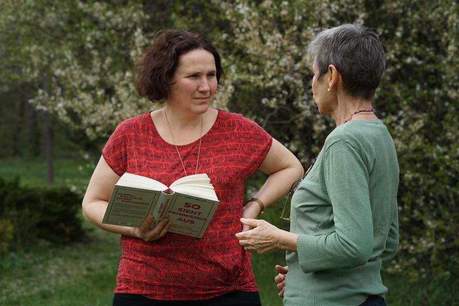Veronika liest aus einem Buch vor und spricht mit einer Frau