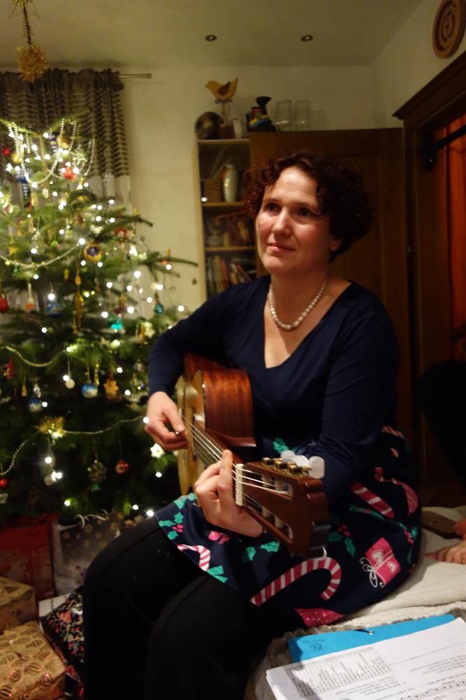 Veronika spielt Gitarre neben einem Christbaum