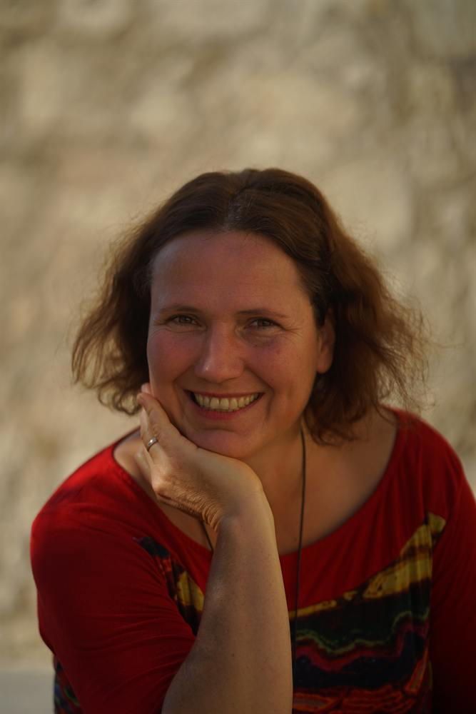 Veronika lächelt, das Kinn auf die Hand gestützt