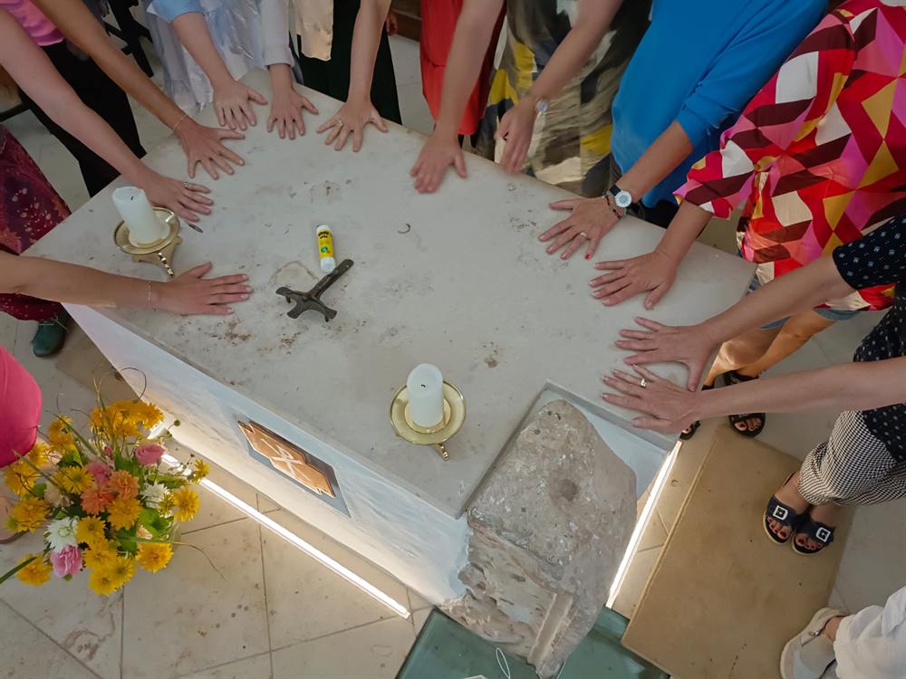 Viele Hände rund um einen Altar mit Blumen